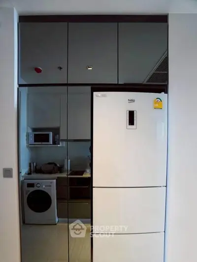 Modern kitchen with sleek appliances including fridge, microwave, and washing machine.
