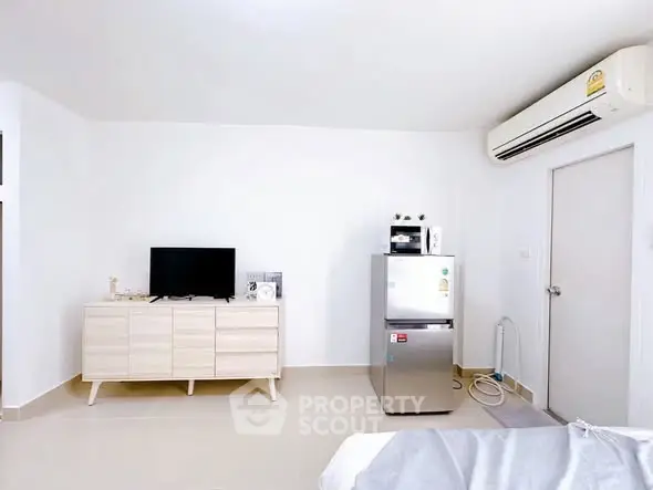 Modern living room with sleek furniture and appliances, featuring a TV and air conditioning unit.