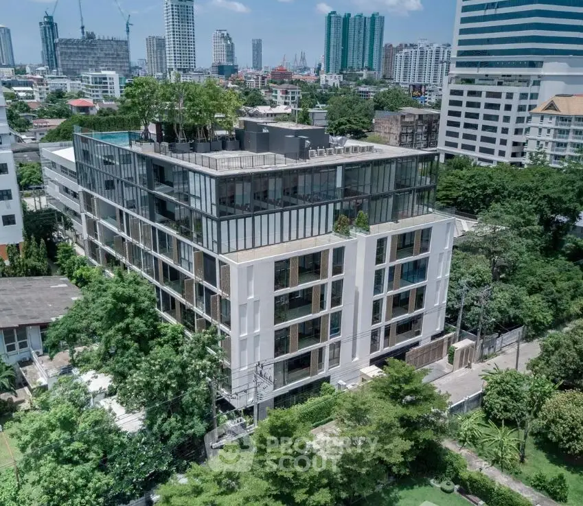 Modern urban building with rooftop greenery and city skyline view.
