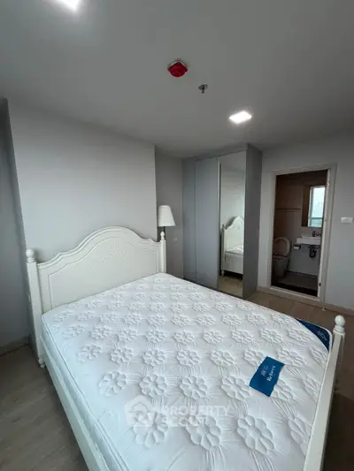Modern bedroom with elegant white bed and mirrored wardrobe in a stylish apartment.