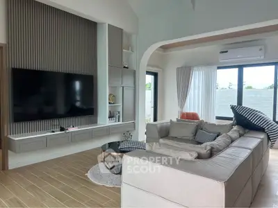 Spacious modern living room with large TV and stylish sectional sofa, perfect for relaxation and entertainment.