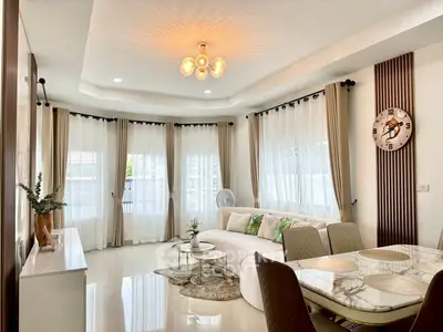 Elegant living room with modern decor, large windows, and stylish dining area