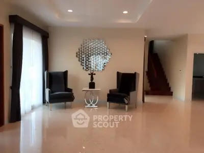 Elegant living room with modern chairs and decorative mirror, featuring polished floors and ambient lighting.