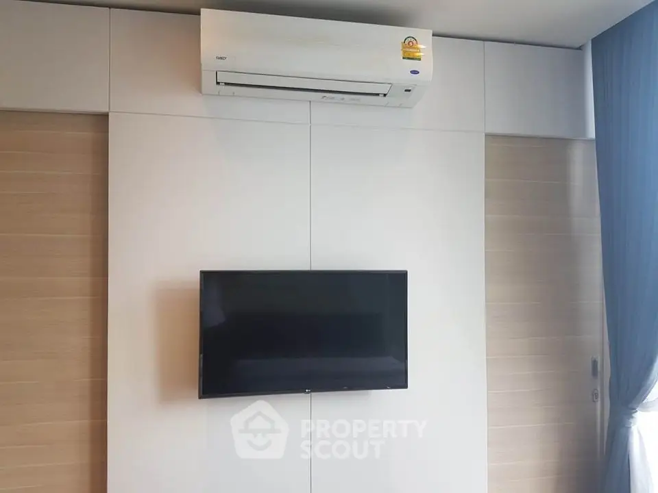 Modern living room with wall-mounted TV and air conditioning unit.