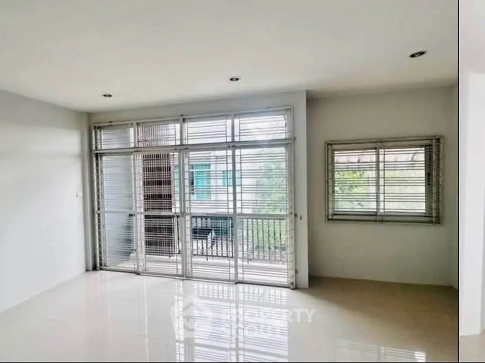 Spacious living room with large windows and balcony access, perfect for natural light.