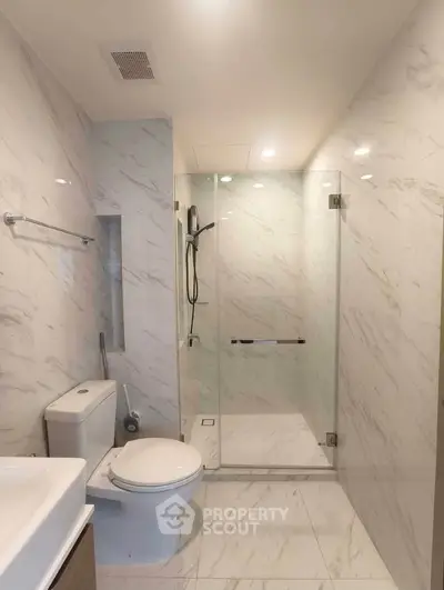 Modern bathroom with glass shower and marble tiles, featuring sleek fixtures and elegant design.