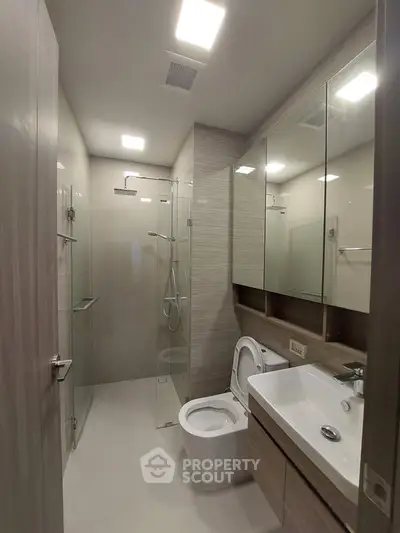 Modern bathroom with glass shower and sleek fixtures in a contemporary apartment.