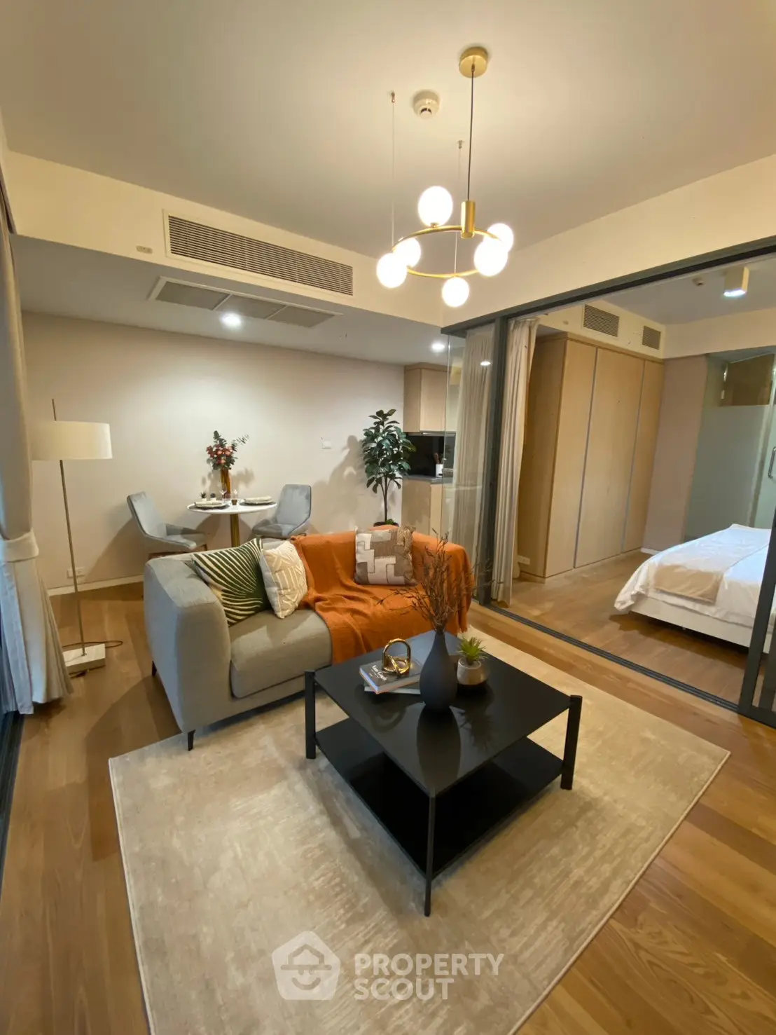 Modern living room with stylish decor and open layout leading to a cozy bedroom.
