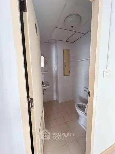 Compact bathroom with white tiles and basic fixtures, ideal for small apartments.
