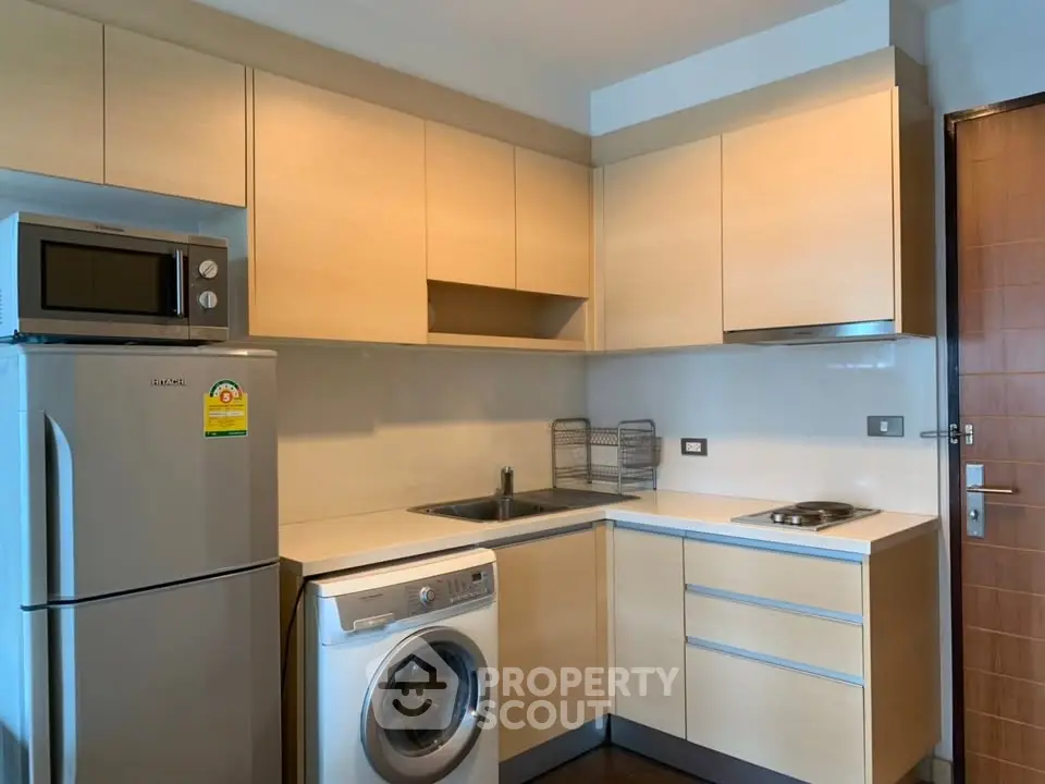 Modern kitchen with appliances including fridge, microwave, and washing machine.