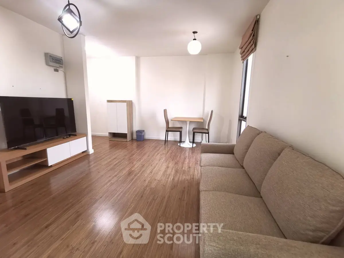 Spacious living room with modern furniture and wooden flooring in a bright apartment.
