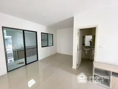 Spacious and bright living area with large sliding glass doors leading to a balcony, featuring a sleek built-in shelf and a glimpse into a modern bathroom.