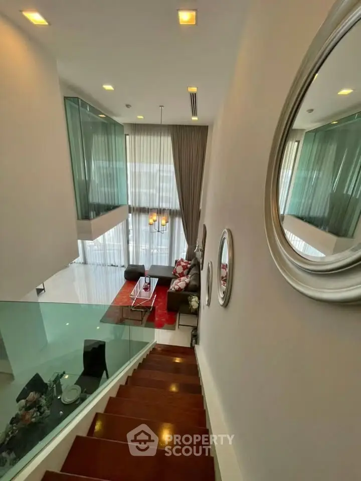 Stunning modern living room with high ceilings and elegant decor, featuring a stylish staircase and large windows.