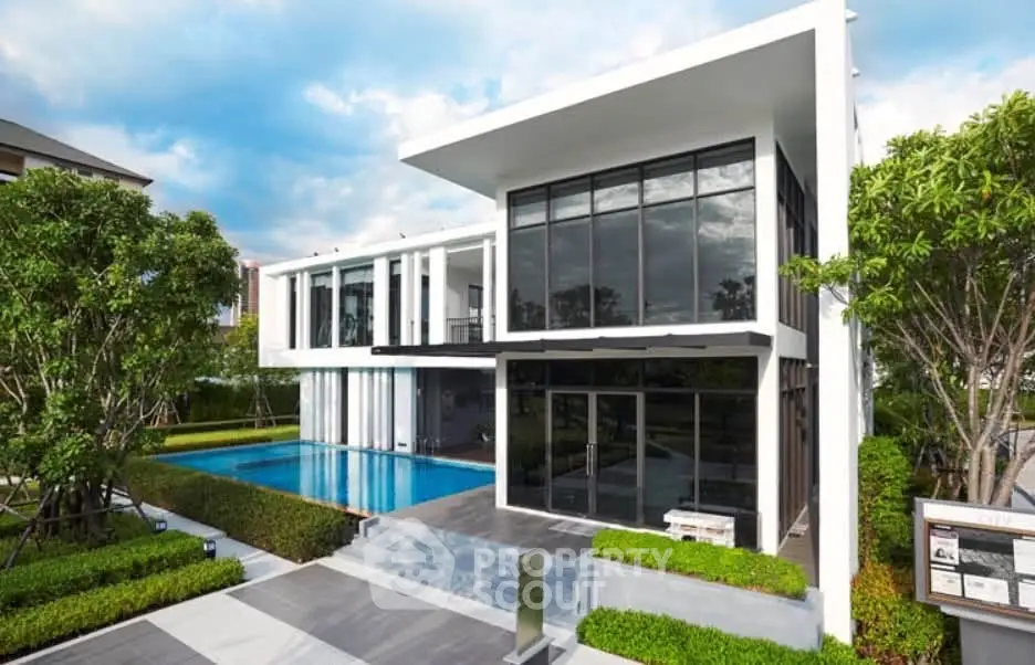 Modern luxury home with sleek architecture and private pool, surrounded by lush greenery and contemporary design.