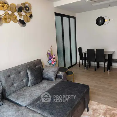Modern living room with stylish decor and dining area, featuring a plush grey sofa and elegant wall art.