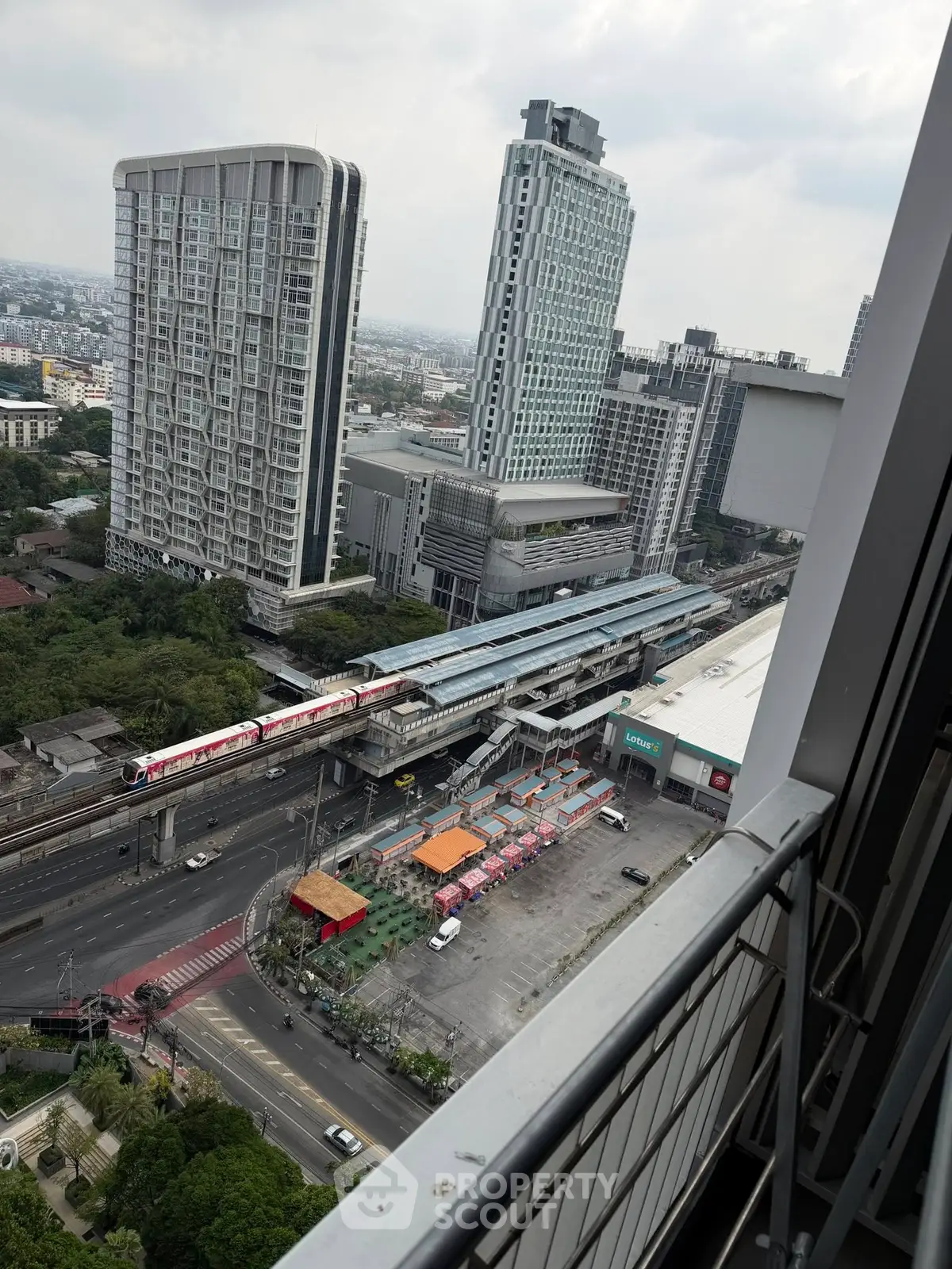 Stunning cityscape view from high-rise balcony overlooking urban skyline and train station.