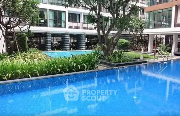 Luxurious apartment complex with serene pool and lush garden view.