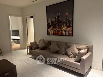 Modern living room with stylish sofa and cityscape artwork, leading to a cozy bedroom.