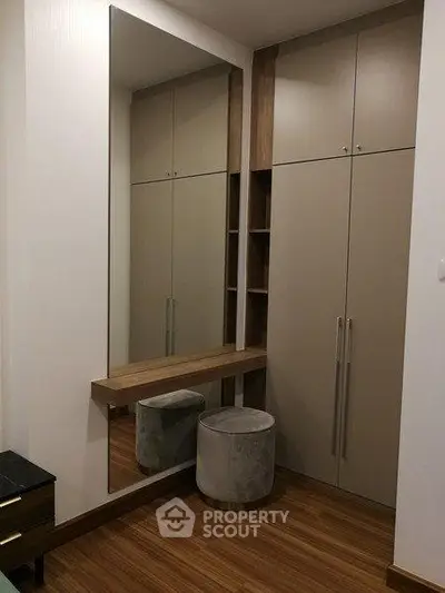 Stylish modern closet with mirror and seating in a contemporary home interior.