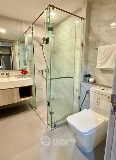 Modern bathroom with glass shower and sleek fixtures in luxury apartment.