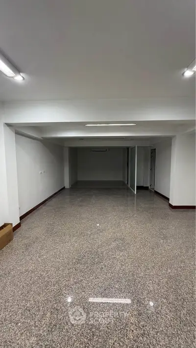 Spacious empty room with polished flooring and bright lighting, ideal for customization.