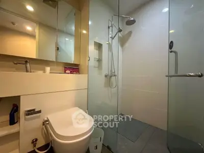 Modern bathroom with glass shower and sleek fixtures in a contemporary apartment.