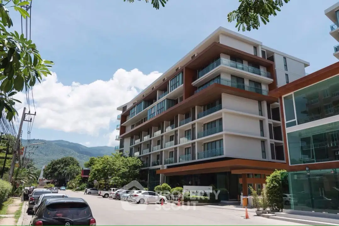 Modern multi-story apartment building with balconies and mountain view in a serene neighborhood.