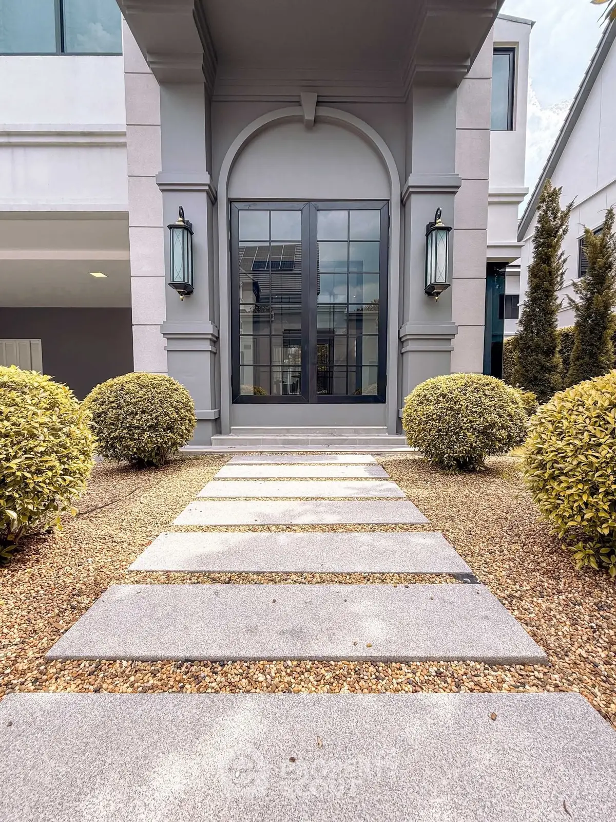 Elegant modern building entrance with stylish pathway and manicured shrubs