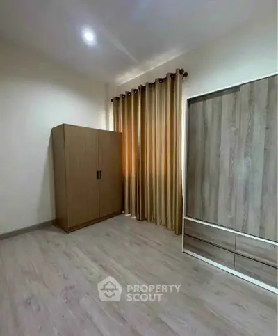 Spacious bedroom with wooden wardrobe and elegant curtains, perfect for modern living.