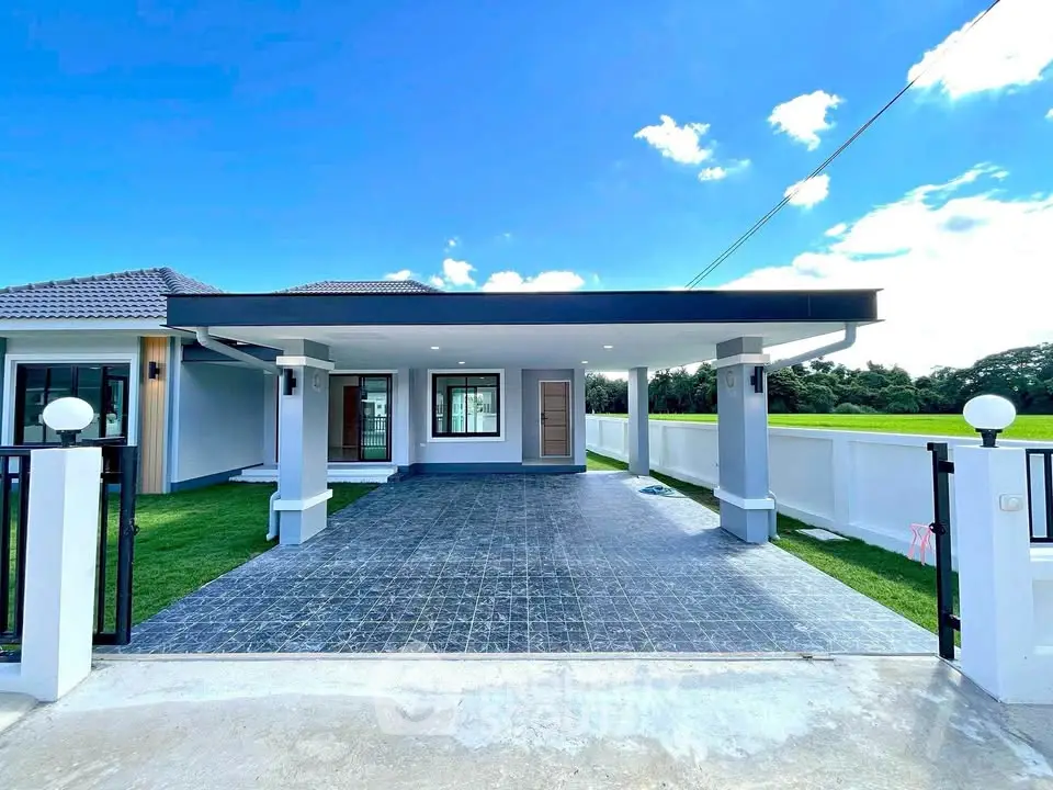 Modern single-story house with spacious driveway and lush green surroundings.