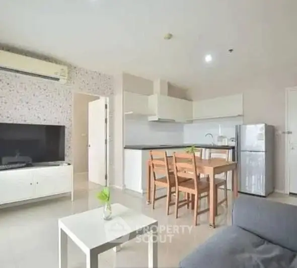 Modern open-layout living room with kitchen, featuring sleek furniture and bright decor.