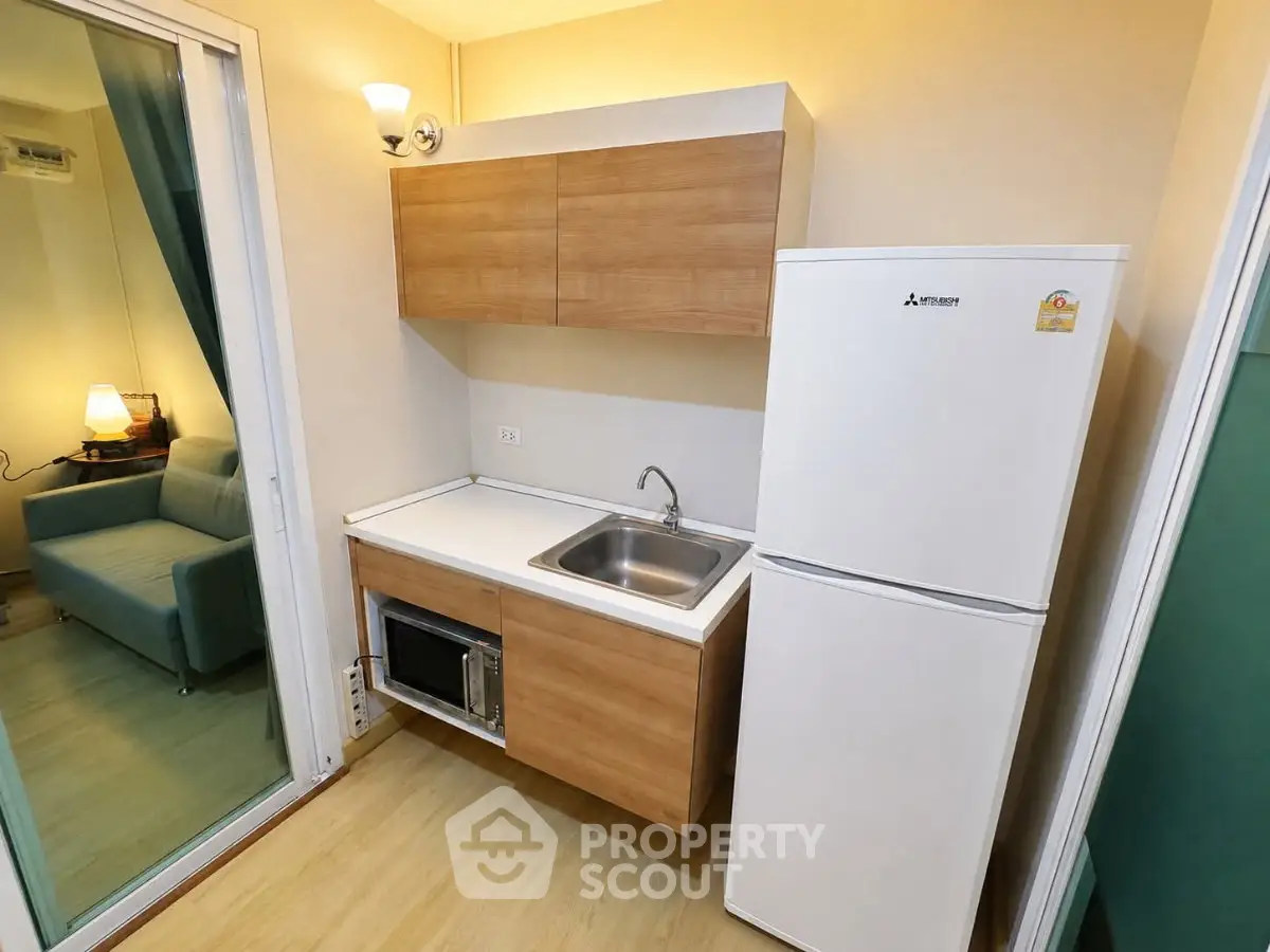 Compact kitchen with modern appliances and wooden cabinetry in cozy apartment