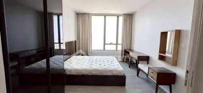 Spacious modern bedroom with large window and stylish furniture in a high-rise apartment.
