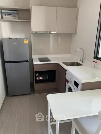 Modern compact kitchen with appliances including fridge, washing machine, and microwave in a sleek design.