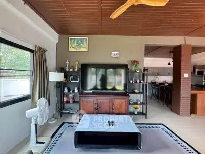 Spacious living room with modern decor and large TV, open layout to kitchen area, perfect for entertaining.