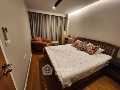 Spacious bedroom with modern wooden bed, cozy armchair, elegant curtains, and ambient lighting, perfect for relaxation.