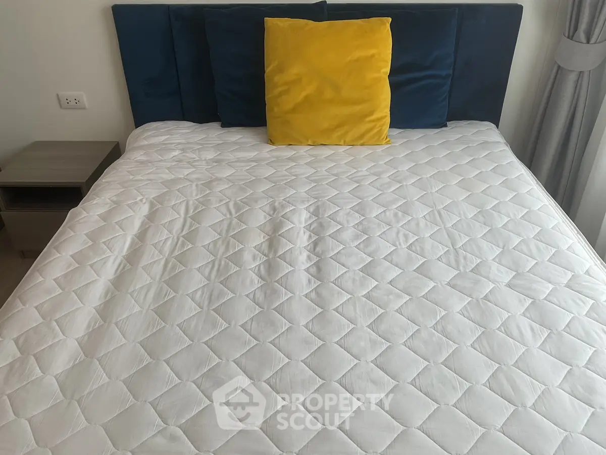Cozy bedroom with stylish blue headboard and vibrant yellow pillow for a modern touch.