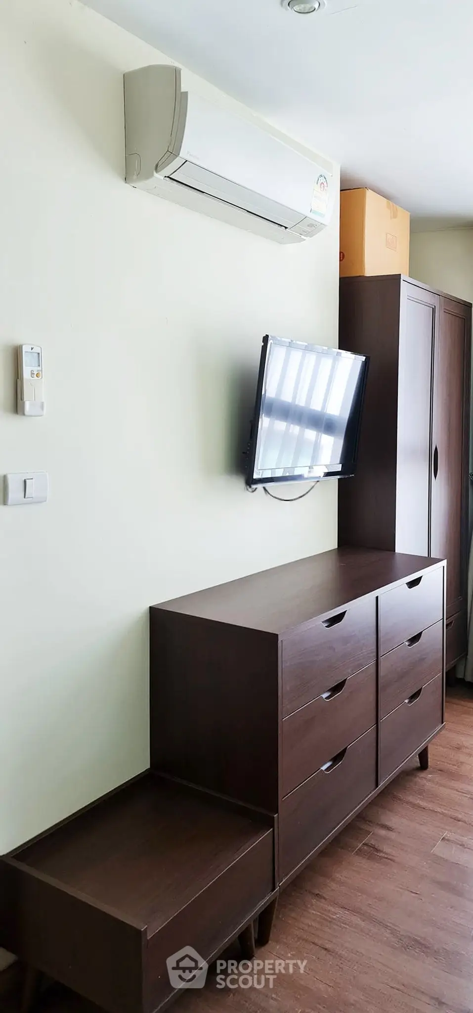 Modern bedroom with sleek dresser, wall-mounted TV, and air conditioning unit.