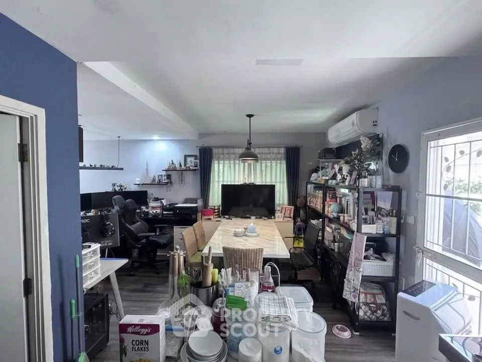 Spacious living room with modern decor and ample natural light, featuring a large dining table and entertainment area.