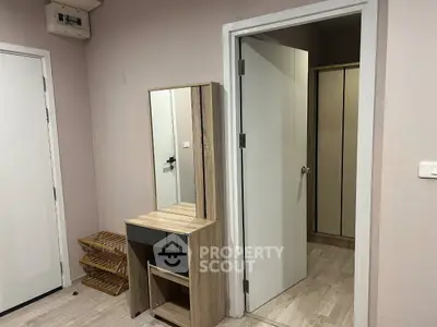 Modern bedroom with wooden vanity and open door leading to closet area.