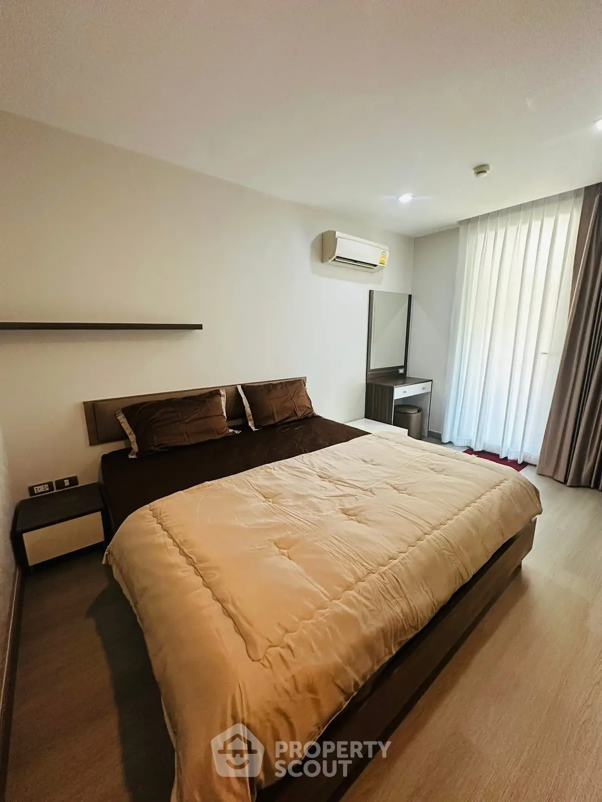 Modern bedroom with cozy bedding and natural light, featuring a sleek air conditioning unit and stylish decor.