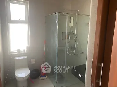 Modern bathroom with glass shower enclosure and large window for natural light.