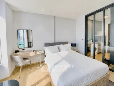 Modern bedroom with natural light and sliding glass doors to kitchen area.