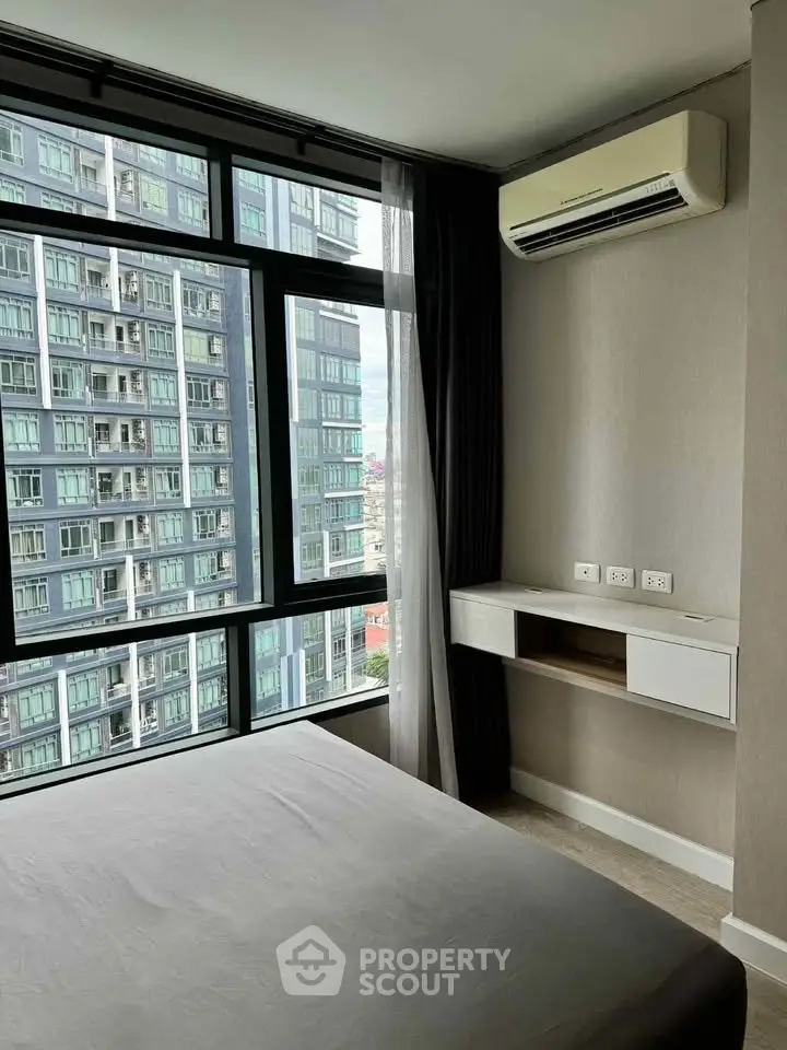 Modern bedroom with large windows and city view in high-rise apartment