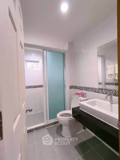 Modern bathroom with sleek design, featuring a spacious shower and elegant sink area.