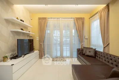 Modern living room with elegant decor, large TV, and natural light through sheer curtains.