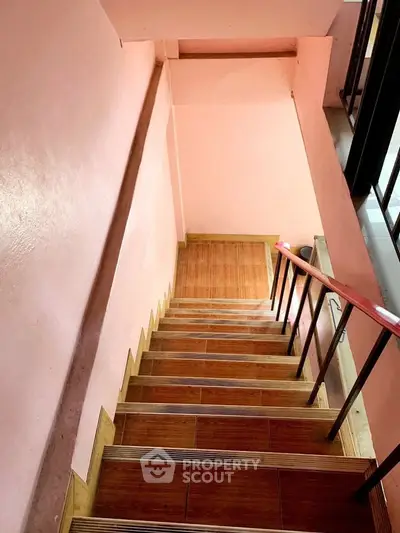 Charming staircase with wooden steps and pink walls in a cozy residential building.