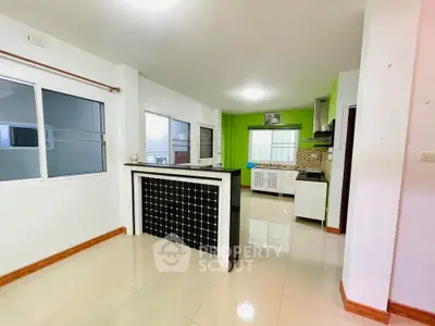 Spacious kitchen with modern design and open layout, featuring sleek countertops and vibrant green accents.
