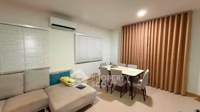Cozy living room with modern furniture and dining area, featuring neutral tones and elegant curtains.
