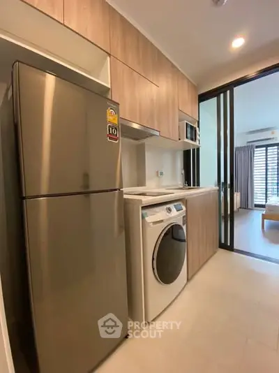Modern kitchen with stainless steel fridge and washing machine in sleek apartment
